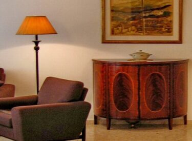 עיצוב הסלון: המנורה עומדת מאירה כורסא גדולה, ושידה עם עבודת פורניר מרהיבה
