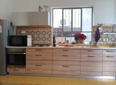 המטבח: פורניר עץ, קלפה עליונה מפורמיקה מתכתית משתלבת עם המקרר מנרוסטה