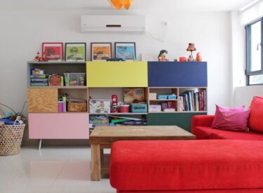 ארון ספרים וצעצועים צבעוני ושמח בחדר משפחה.