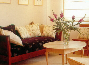 פינה בסלון: בדי ריפוד בדוגמאות מעורבות, קיר ירוק-זית עם מסגרת לבנה, ריהוט עץ מייפל שיובא מארה