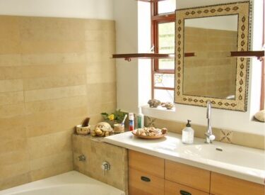 חדר אמבטיה עם אריחי אבן וחלונות מפרופיל בלגי