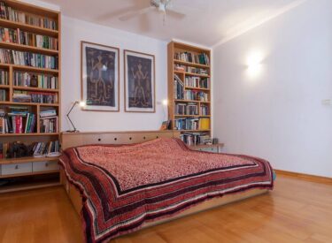 עיצוב חדר שינה: ספריה גדולה משני צידי המיטה, בה משולבות גם השידות