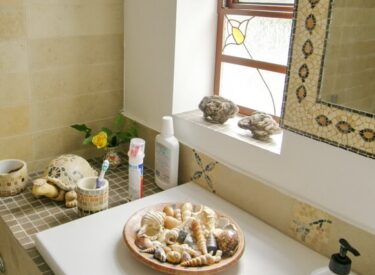 חדר אמבטיה עם אריחי אבן וחלונות מפרופיל בלגי