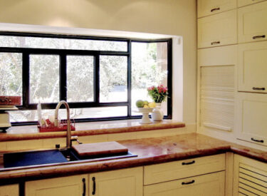 חלון אקווריום גדול נפתח במטבח, מרחיב אותו ומכניס את החוץ פנימה..