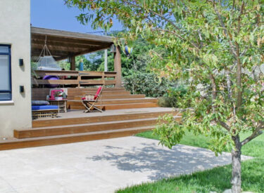 הירידה ממרפסת הסלון לגינה האחורית היא אלמנט מרכזי בתכנון הגינה